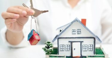 Agente imobiliária segurado chaves e com modelo de casa