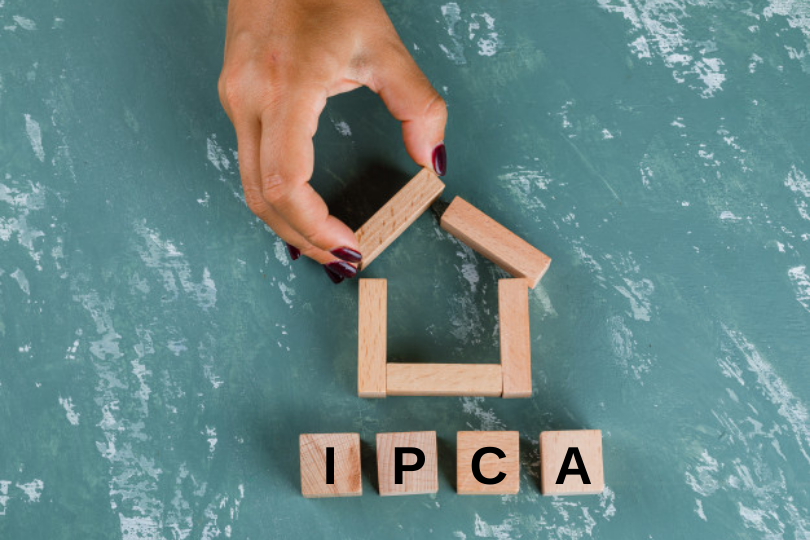 Mão colocando peças para forma um casa. Palavra IPCA sob a casa.